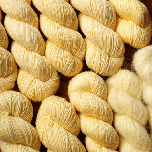 Close-up of butter-yellow yarn skeins on a wooden surface