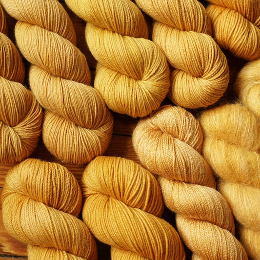 Close-up of skeins of yellow yarn on a wooden surface