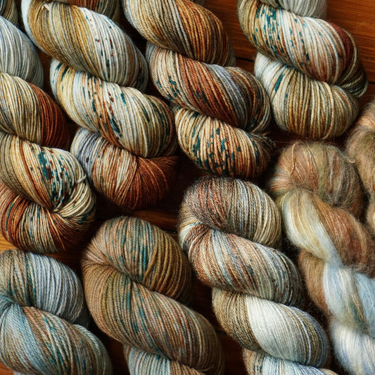 Wool yarn skeins with earthy tones on a wooden surface