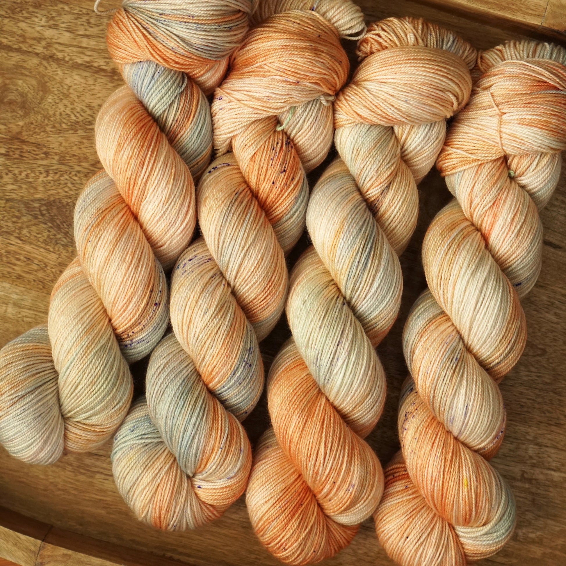 Three skeins of multicolored yarn on a wooden tray